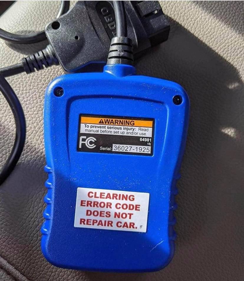 The meme is an image of a car's on-board computer (OBD-II) reader, which is a device used to diagnose problems with a vehicle's engine. The image shows the reader with a warning message on its screen that says "CHECK ENGINE LIGHT IS ON" and "CLEARING CODES...". Below the screen, the reader displays the message "CLEARED 1 CODE" with a notation that says "NO CODES PRESENT".